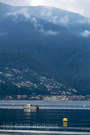 Schweiz, Ascona - Ausflugsdampfer und Boot, herbstliche Stimmung in der Morgendaemmerung am Lago Maggiore