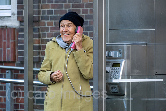 Deutschland, Bremen - Ruestige Rentnerin telefoniert an einer Telefonzelle der Deutschen Telekom