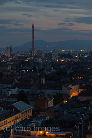 Kroatien, Zagreb - Uebersicht auf Teil des Stadtzentrums in der Abenddaemmerung mit Schornstein eines Kraftwerks, hinten Berge