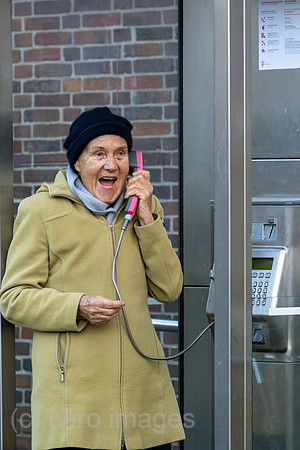 Deutschland, Bremen - Ruestige Rentnerin telefoniert an einer Telefonzelle der Deutschen Telekom
