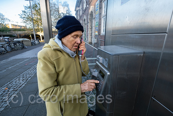 Deutschland, Bremen - Ruestige Rentnerin waehlt eine Nummer an einer Telefonzelle der Deutschen Telekom