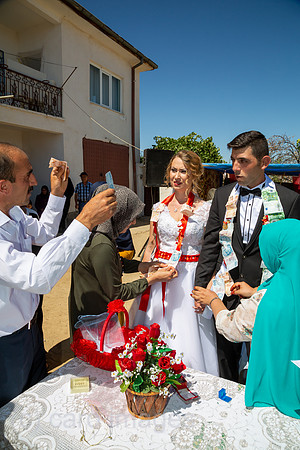 Tuerkei, Bogazkoey Sarıyahsi - Polnisch-tuerkisches Brautpaar bei traditioneller Hochzeit auf dem Dorf in Anatolien, das Paar wird nach einem Brauch mit Geldscheinen dekoriert