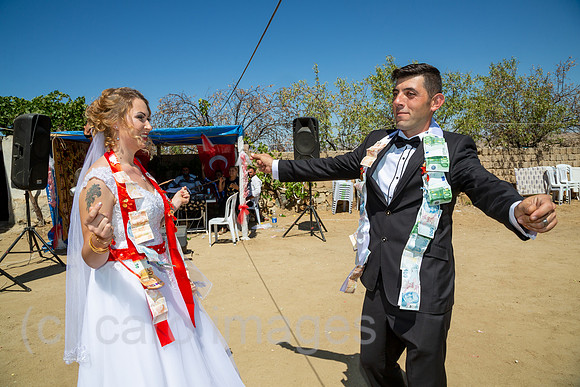 Tuerkei, Bogazkoey Sarıyahsi - Polnisch-tuerkisches Brautpaar tanzt bei traditioneller Hochzeit auf dem Dorf in Anatolien, das Paar ist nach einem Brauch mit Geldscheinen dekoriert