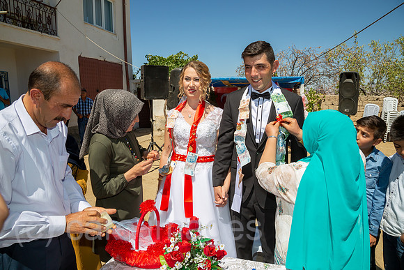 Tuerkei, Bogazkoey Sarıyahsi - Polnisch-tuerkisches Brautpaar bei traditioneller Hochzeit auf dem Dorf in Anatolien, das Paar wird nach einem Brauch mit Geldscheinen dekoriert
