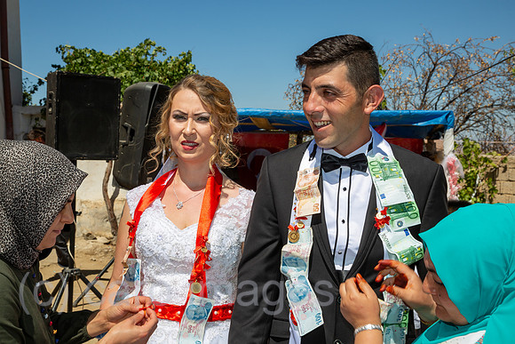 Tuerkei, Bogazkoey Sarıyahsi - Polnisch-tuerkisches Brautpaar bei traditioneller Hochzeit auf dem Dorf in Anatolien, das Paar wird nach einem Brauch mit Geldscheinen dekoriert