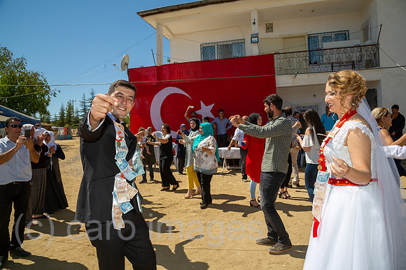 Tuerkei, Bogazkoey Sarıyahsi - Polnisch-tuerkisches Brautpaar tanzt bei traditioneller Hochzeit auf dem Dorf in Anatolien, das Paar ist nach einem Brauch mit Geldscheinen dekoriert