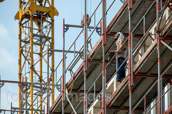 Deutschland, Bremen - Baustelle, Bauarbeiter bedient Ladekran mit Joystick, Baustelle fuer Gewerbeimmobilie am Flughafen