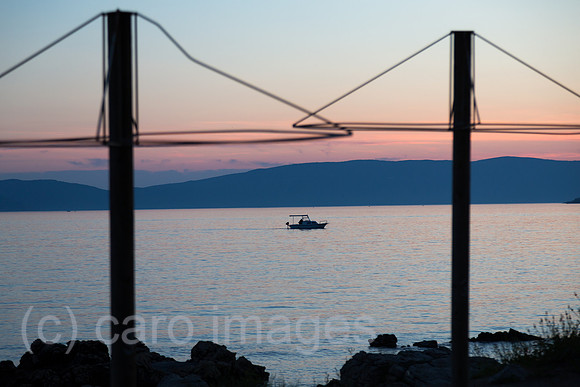 Kroatien, Krk (Hauptstadt der Insel Krk) - Blick auf die Bucht vor Krk mit einem Boot, vorne Staender fuer Sonnenschirme