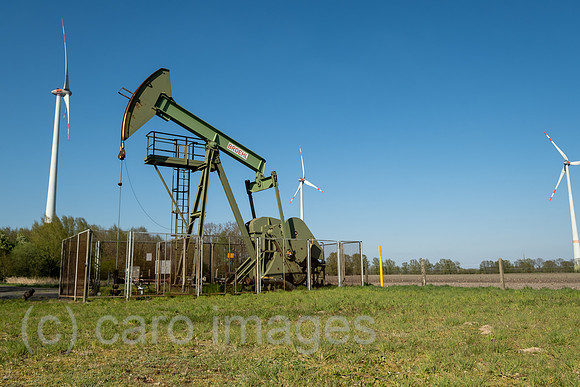Deutschland, Barenburg - Erdoelproduktionsbohrung von Exxon Mobile mit einer Pferdekopfpumpe, hinten Windraeder