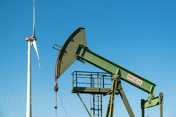Deutschland, Barenburg - Erdoelproduktionsbohrung von Exxon Mobile mit einer Pferdekopfpumpe, hinten ein Windrad