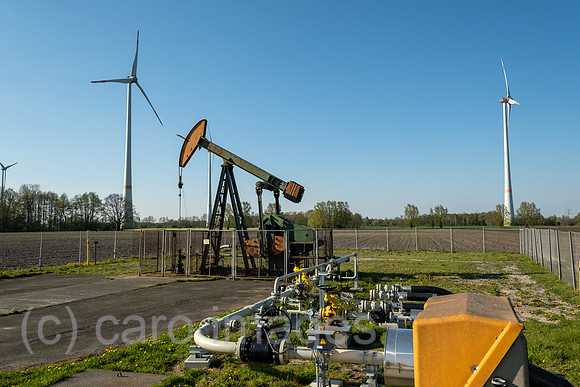 Deutschland, Barenburg - Erdoelproduktionsbohrung von Exxon Mobile mit einer Pferdekopfpumpe, hinten Windraeder