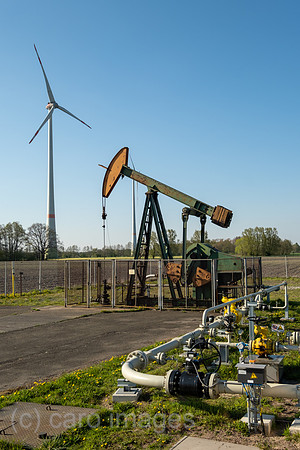Deutschland, Barenburg - Erdoelproduktionsbohrung von Exxon Mobile mit einer Pferdekopfpumpe, hinten ein Windrad