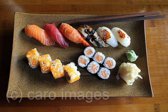Berlin, Deutschland, Sushi und Essstaebchen auf einem braunen Teller
