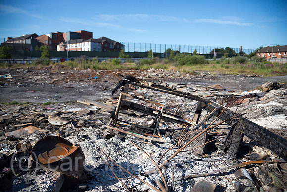 Grossbritannien, Nordirland, Belfast - Protestantischer Teil von West Belfast - verwahrloster, verbrannter Platz nach dem bonfire vom Orangemens Day, hinten der Peace Wall