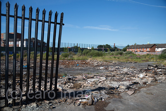 Grossbritannien, Nordirland, Belfast - Protestantischer Teil von West Belfast - verwahrloster, verbrannter Platz nach dem bonfire vom Orangemens Day, hinten der Peace Wall
