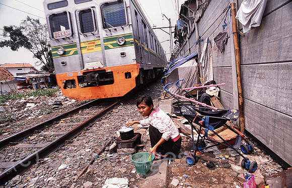 Jakarta, Indonesien, Frau kocht Reis im Elendsviertel entlang der Bahnschienen