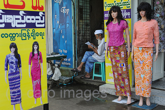 Yangon, Myanmar, Mann liest neben Schaufensterpuppen fuer Damenm