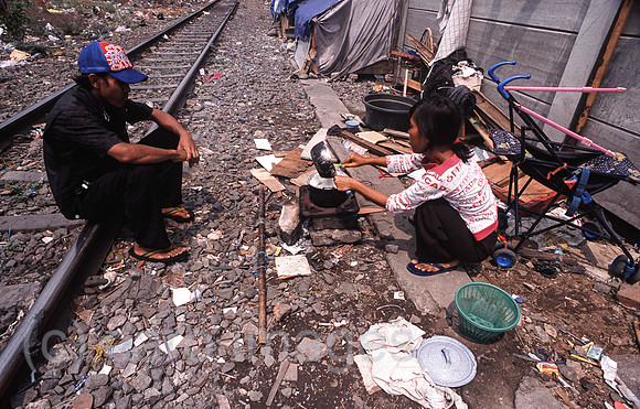 Jakarta, Indonesien, Frau kocht Reis im Elendsviertel entlang der Bahnschienen