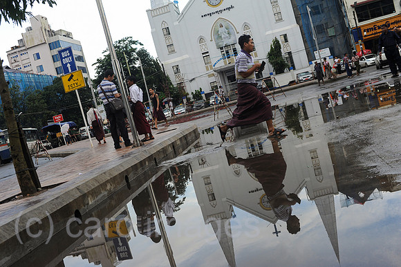Yangon, Myanmar, Mann rennt waehrend Regenzeit durch eine Pfuetze