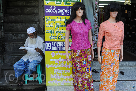Yangon, Myanmar, Mann liest neben Schaufensterpuppen fuer Damenm