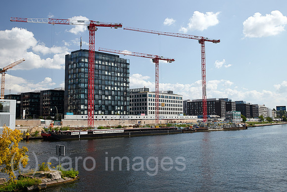 Berlin, Deutschland - Blick ueber die Spree auf neu erbaute Buerogebeaude und Baustellen am Flussufer in Berlin-Friedrichshain.