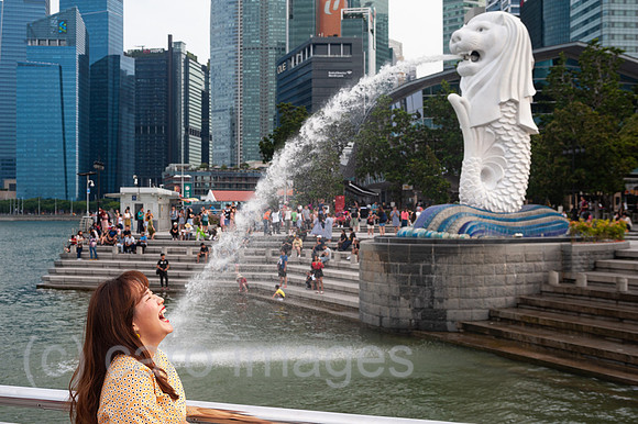 Singapur, Republik Singapur, Tourist posiert fuer Foto im Merlion Park in Marina Bay