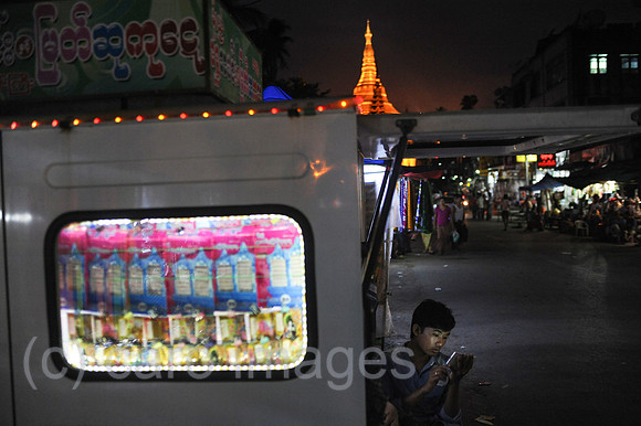 Yangon, Myanmar, Losverkaeufer auf Nachtmarkt mit Shwedagon-Pago