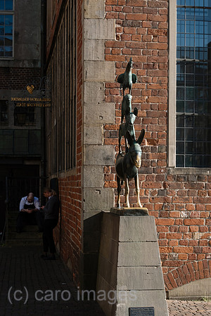 Deutschland, Bremen - Das bekannteste Wahrzeichen der Stadt, die Skulptur der Bremer Stadtmusikanten, Symbol der Freiheitsliebe und Unabhaengigkeit, hinten Angestellte der Gastronomie