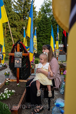 Ukraine, Lwiw - Witwe mit Tochter trauert am Grab ihres Manns auf dem Marsfeld, Ehrenfriedhof der gefallenen Lwiwer Soldaten im Ukrainekrieg