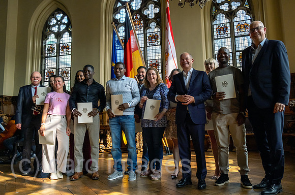 Deutschland, Bremen - Einbuergerungsfeier in der in der Oberen Rathaushalle, im Bild Neubuerger mit der Einbuergerungsurkunde, rechts Bundeskanzler Olaf Scholz, ganz rechts Bremer Buergermeister Andre