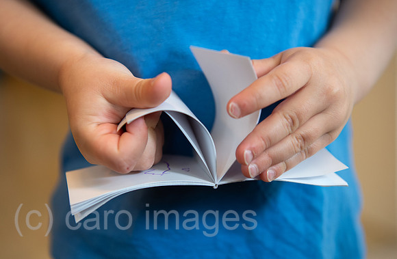 Berlin, Deutschland - Kinderhaende blaettern in einem Notizbuch