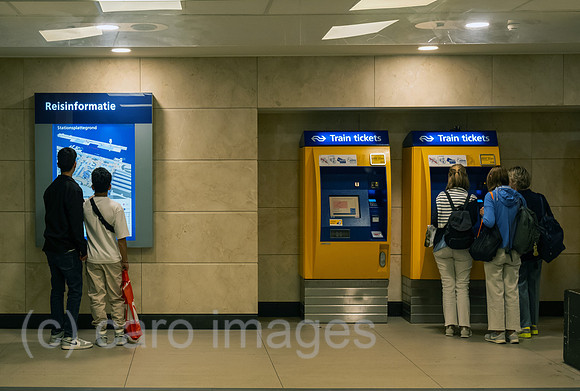Niederlande, Amsterdam - Passagiere vor Fahrscheinautomaten und einem Bildschirm mit Reiseinformation in der Centraal Station (Hauptbahnhof)