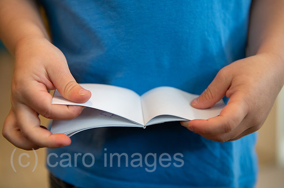 Berlin, Deutschland - Kinderhaende blaettern in einem Notizbuch