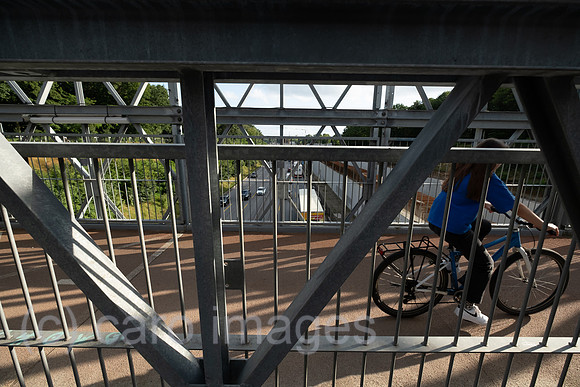 Deutschland, Hamburg - Fahrradfahrerin auf einer Bruecke fuer Fussgaenger und Fahrradfahrer ueber eine Autobahn