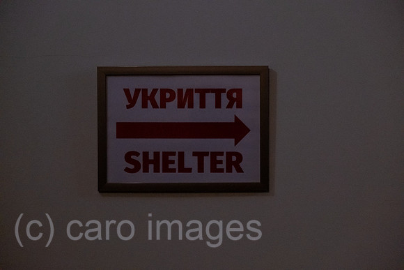 Ukraine, Lwiw - english-ukrainisches Hinweisschild in Hotel zum Luftschutzraum bei schummriger Beleuchtung nach Stromausfall