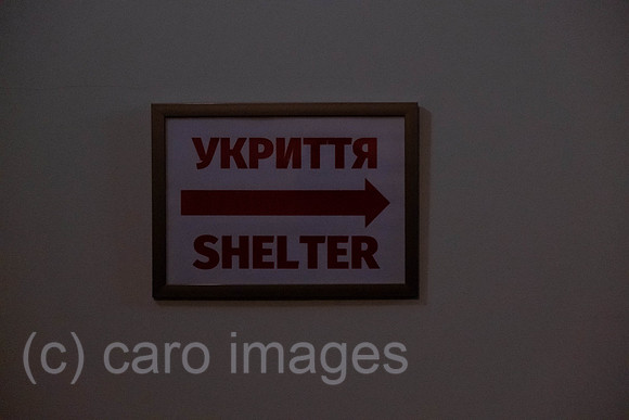 Ukraine, Lviv - English-Ukrainian sign in a hotel for the air-raid shelter in dim lighting after a power outage