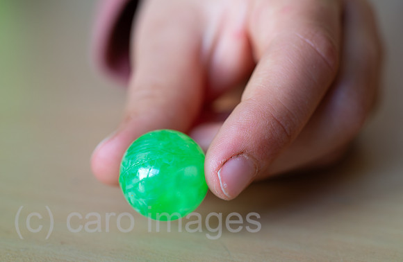 Berlin, Deutschland - Kinderhand mit gruener Glasmurmel